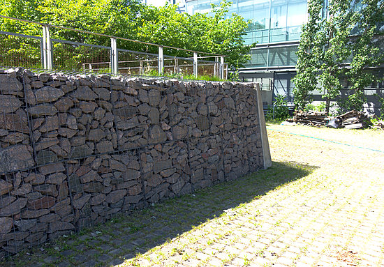 Suurikokoisista kivistä koottu muuri tukevassa metalliverkossa