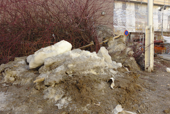 Pensas johon on ajettu lunta ja heitetty rakennustyömaan roskia